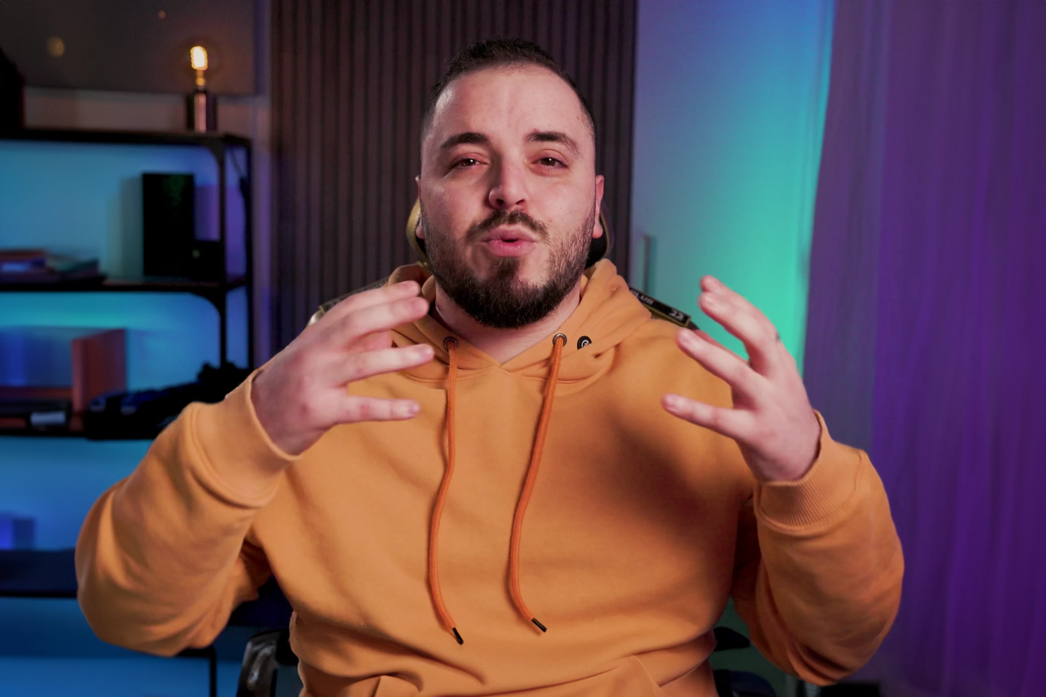 Nabil Khaled recording content at his desk in an orange hoodie