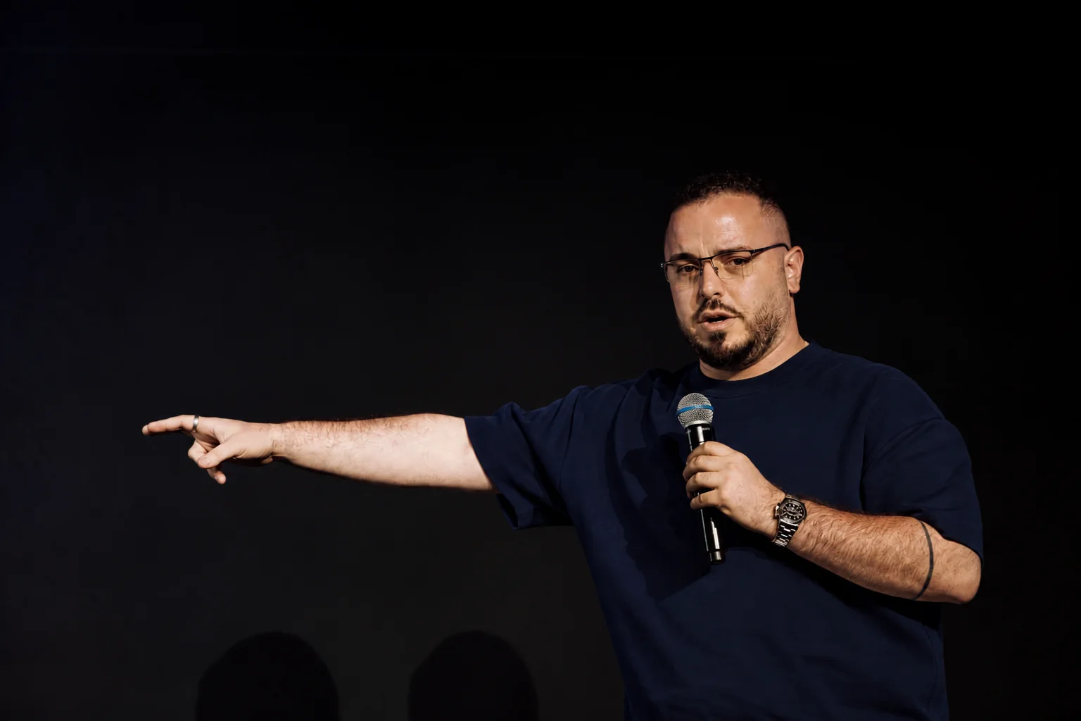 Nabil Khaled on stage, pointing while speaking into a microphone